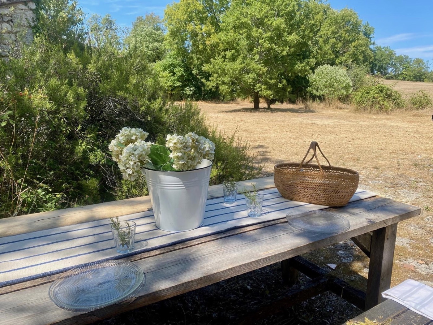 Outdoor wooden table with flowers overlooking the gardens at Le Petit Capelier